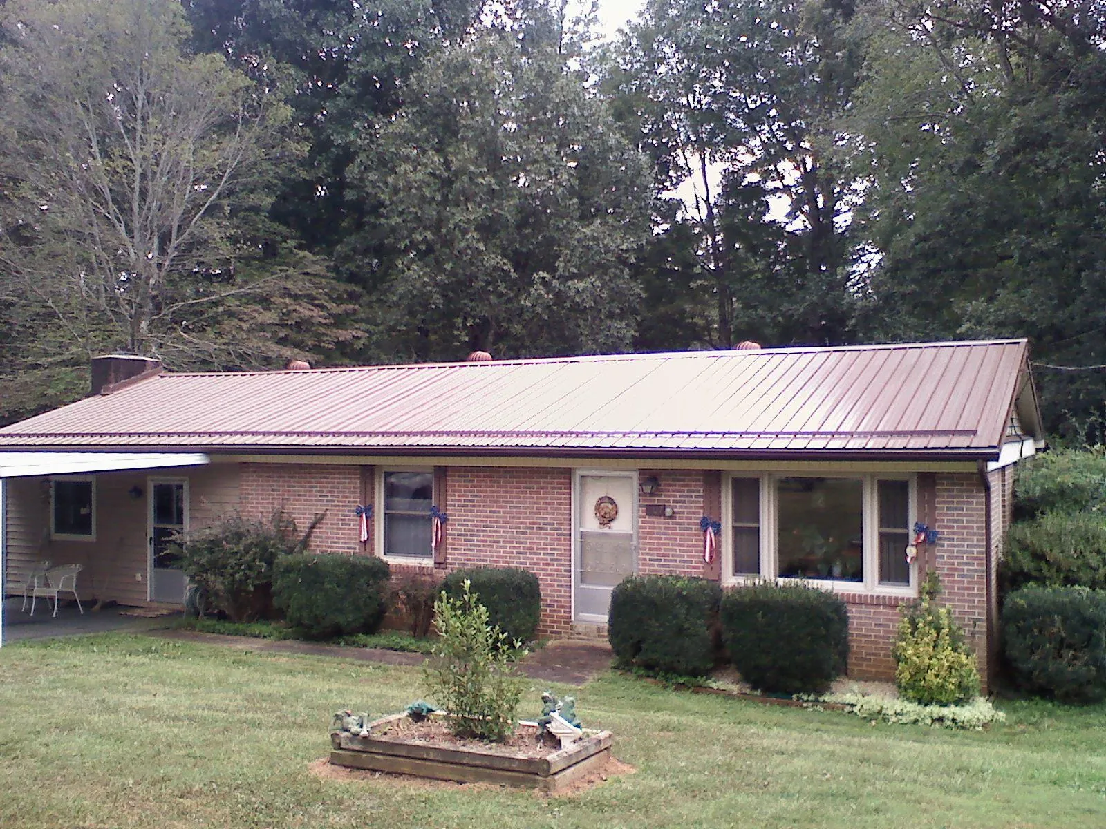 Bronze metal roof on a brick ranch home with a carport in Thornton